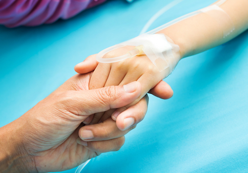 Adult hand holding child's hand with IV
